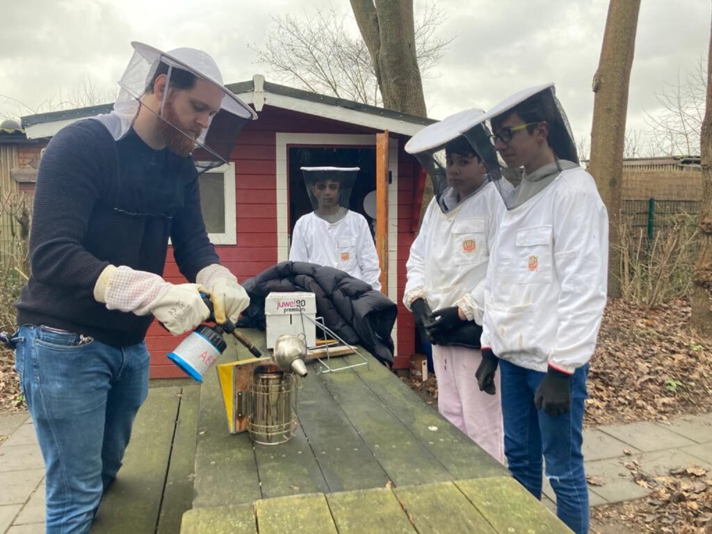 Lehrer Jan-Max Gramberg trifft mit den Schülern Giuseppe (15), Lorenzo (13) und Nasser (13, von links) Vorbereitungen, um die zwei Bienenstöcke zu besuchen.