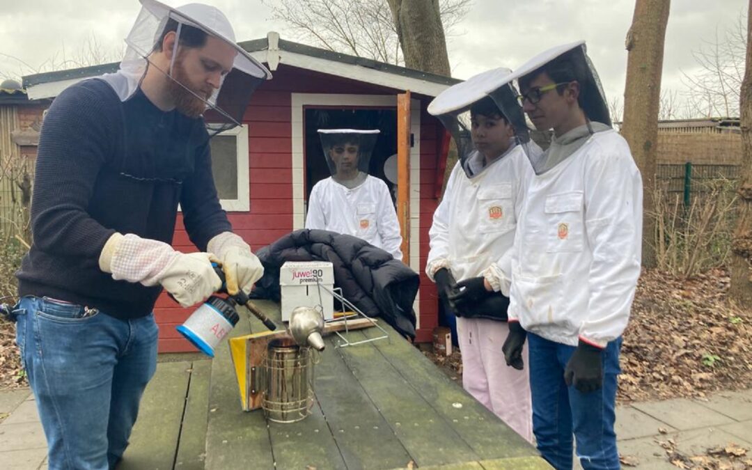 Lehrer Jan-Max Gramberg trifft mit den Schülern Giuseppe (15), Lorenzo (13) und Nasser (13, von links) Vorbereitungen, um die zwei Bienenstöcke zu besuchen.