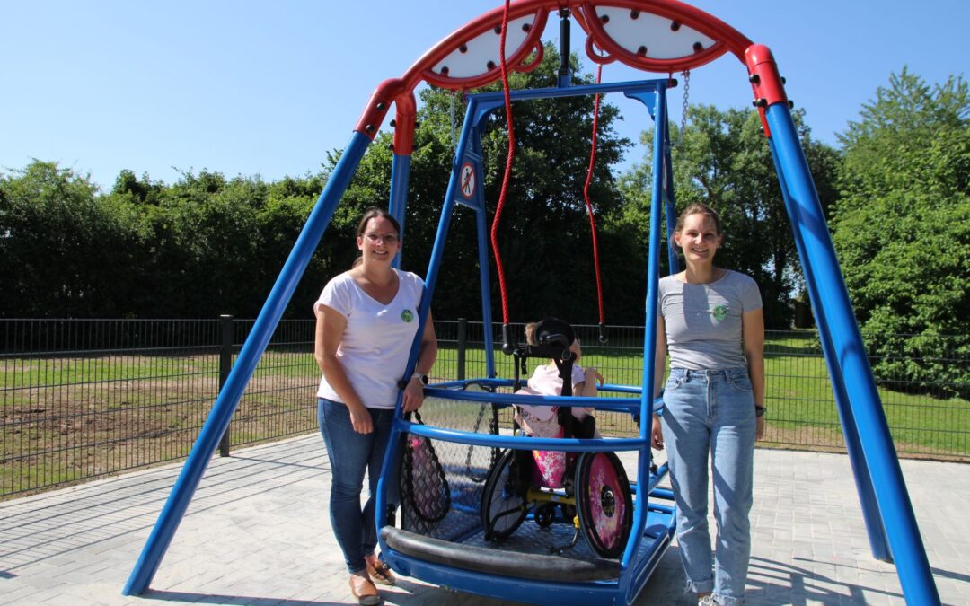 zwei Frauen stehen neben einer Rollstuhlschaukel, auf der ein Kind schaukelt
